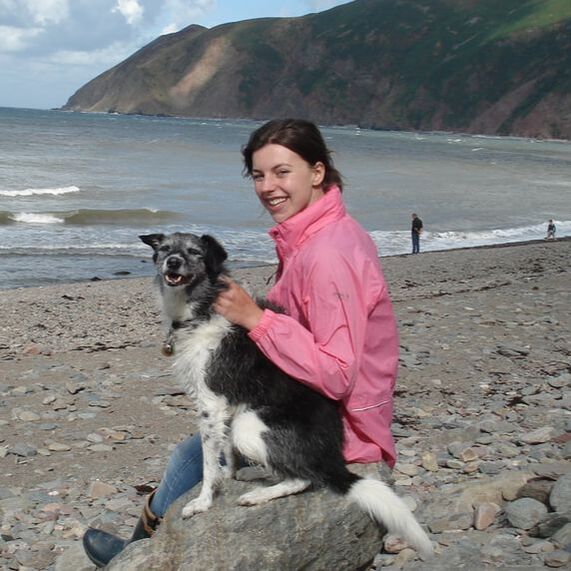 Image of Dr. Emma Ireland on a beach with a black and white dog